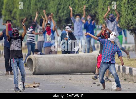 Un manifestant musulman du Cachemire lance des pierres sur les troupes indiennes comme d'autres crier des slogans pro liberté à Srinagar, au Cachemire sous contrôle indien Banque D'Images