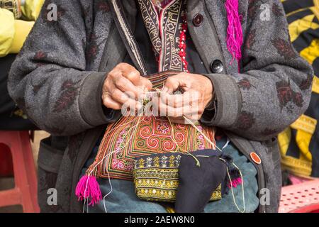 Minorités ethniques dzao rouge couture femme à Sa Pa, province de Lao Cai, Vietnam. Une femme âgée coud sur la rue. Faire de belles broderies comme un souveni Banque D'Images