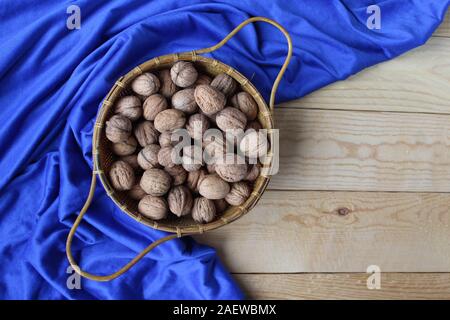 Vue d'en haut d'un panier de noix en coque, sur une table en bois avec un fond de classique bleu tapis de table. La nature des aliments. Avec copyspace Banque D'Images