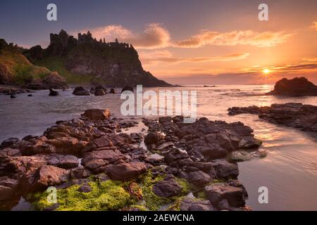 Les ruines de la château de Dunluce sur la côte de Causeway d'Irlande du Nord. Photographié au coucher du soleil. Banque D'Images