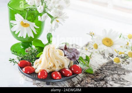 Soft blanc traditionnel fromage Cecil fibreux se trouve sur une plaque. Le fromage est décorée avec des tomates mûres et de groseilles. Copier l'espace. Banque D'Images