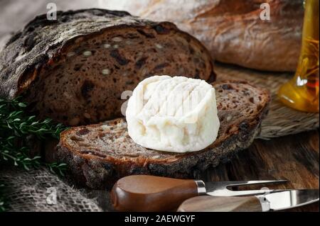 Délicieux fromage rond doux avec la moisissure blanche sur un morceau de pain artisanal à l'huile d'olive. Banque D'Images