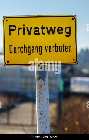 Panneau jaune avec texte allemand 'chemin privé entrée interdite' sur une journée ensoleillée. Out-of-focus chambre avec clôture dans le contexte - gros plan, format vertical Banque D'Images