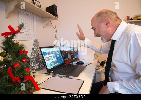 Toujours occupé à travailler loin de la maison juste avant Noël, mais le fait de prendre une pause pour faire du chat vidéo avec les membres de la famille. Banque D'Images