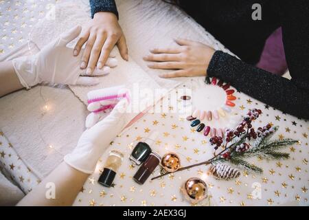 Manucure femelle prêt à travailler les ongles de femme. Womens manucure mains tenant les mains de womans et pinceau rose ongle sur le tableau d'étoiles, vernis à ongles, c Banque D'Images