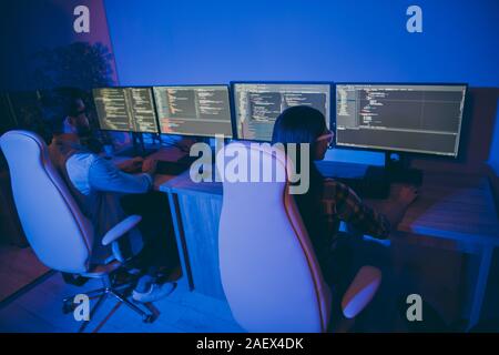 Voir photo de l'arrière derrière elle des gens d'affaires lady guy spécialiste travaillant de nuit ensemble fauteuils nombre de moniteurs du système de test écrit Banque D'Images