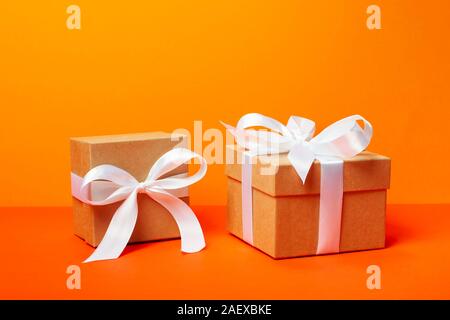 Cadeaux tendance minimaliste attrayant sur fond orange. Joyeux Noël, la Saint-Valentin, joyeux anniversaire et autres fêtes concept. Banque D'Images