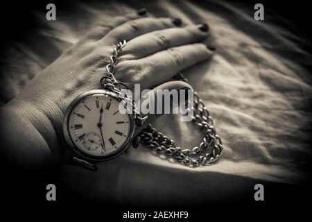 Une photo en noir et blanc de a woman's hand holding a retro pocket watch Banque D'Images