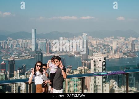 Hong Kong, Chine - Novembre 2019 : PHappy asian family posing for photo avec vue sur les toits de Hong Kong à partir de la plate-forme d'observation de pointe au cours de Hong K Banque D'Images