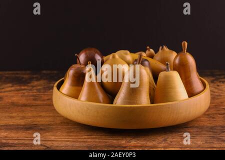 Un bol de fruits en bois sculpté à la main sur une table en bois. Pomme, poire, prune, citron, grenade et la banane Banque D'Images