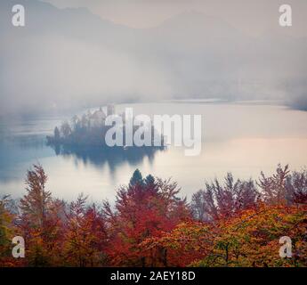 Voir l'église de l'assomption de Marie sur le lac de Bled. Paysage d'automne brumeux dans les Alpes Juliennes, en Slovénie, en Europe. Style artistique poste a traité la photo. Banque D'Images