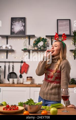 Femme en cornes de cerf de noël vin boissons debout dans la cuisine. Nouveau concept de l'année Banque D'Images