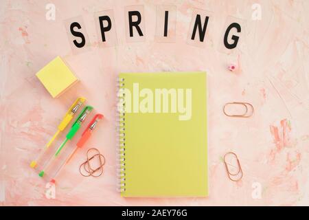 Mot de printemps et d'étudiants de l'espace de bureau avec ordinateur portable et stylos sur un fond rose. Mise à plat, vue du dessus, les médias sociaux hero modèle d'en-tête. Banque D'Images