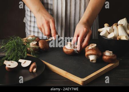 Femme coupe champignon sur une planche à découper avec des champignons, Close up Banque D'Images