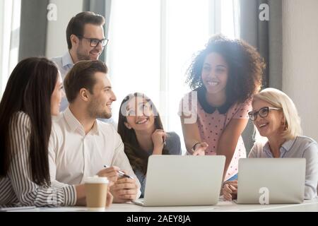 Smiling divers employés travaillaient ensemble à rire laptop in office Banque D'Images