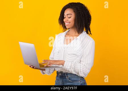 Recherche d'informations. Happy black woman using laptop, le choix de chambre d'hôtel en ligne, réservation de billets Banque D'Images