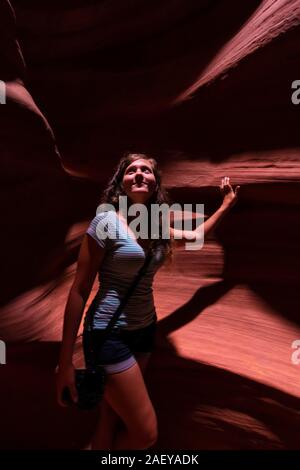 Jeune femme dans la fente d'Antelope Canyon en Arizona l'article tenir l'appareil photo par des formations de grès looking up Banque D'Images