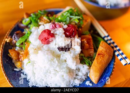 La plaque traditionnelle japonaise sur table en bois aux légumes avec du riz blanc, baguettes, umeboshi shiso et pousses de bambou d'oignons verts Banque D'Images