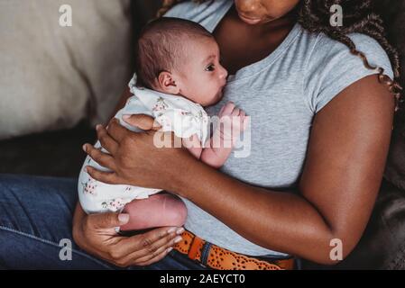 Maman en bleu shirt noir multiraciale holding newborn Banque D'Images