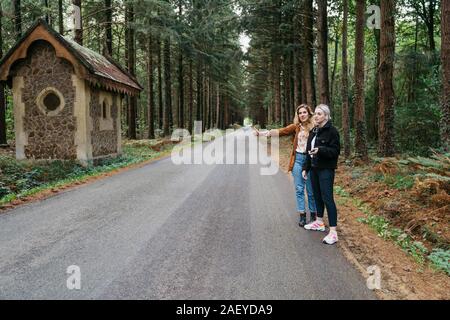 Deux femmes de l'auto-stop sur une route forestière en France Banque D'Images