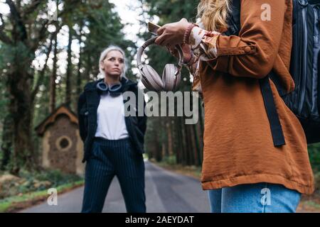 Woman holding smartphone et casque sur une route dans la campagne Banque D'Images