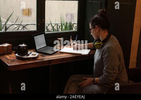 Les jeunes l'étudiant est inscrit dans un café avec son portable Banque D'Images