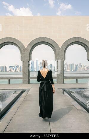 Vue arrière de jeune femme marchant et regardant la mer à Doha Banque D'Images