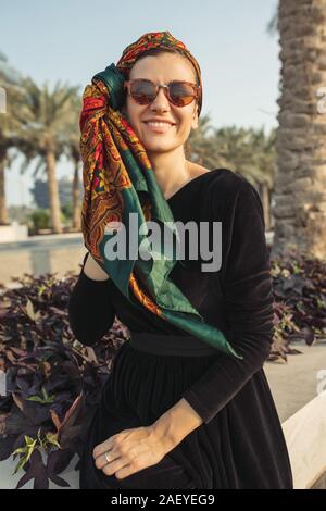 Young smiling woman wearing headwrap assis sur le mur Banque D'Images