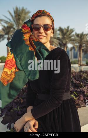 Young smiling woman wearing headwrap assis sur le mur Banque D'Images