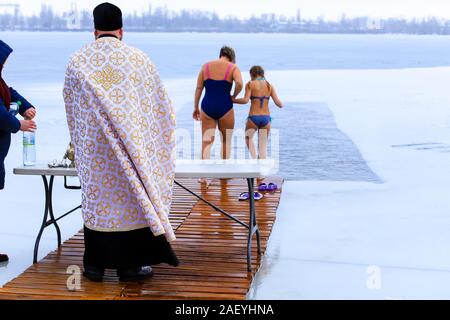 Les gens se baigner dans la rivière durant l'Epiphanie orthodoxe, un prêtre à l'église lit vêtements une prière et sanctifie l'eau. Sports d'hiver, natation, t Banque D'Images