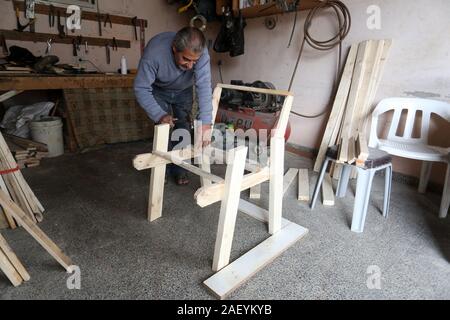 L'homme fait palestinien des chaises de bois, en raison de leur incapacité à acheter de nouveaux bois en raison de la détérioration économique, dans la bande de Gaza. Banque D'Images