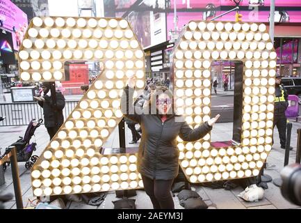 Une femme portant des lunettes 2020 prend une photo de l'enfant debout deux et zéro de l'année 2020 les chiffres quand ils sont allumés dans Times Square à New York le Mercredi, Décembre 11, 2019. Le géant, sept pieds de hauteur de '20' est arrivé sur un camion à plateau sur la 46e Rue et Broadway et sera portée à la partie supérieure d'un Times Square où ils vont se reposer quelques jours avant de remplir le '2-0C2-0' qui s'allume à minuit le soir du Nouvel An pour annoncer le début de la nouvelle année à la fin de la balle Drop. Photo de John Angelillo/UPI Banque D'Images