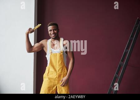 Montrant au large de l'apa. Young african american travailleur dans l'uniforme jaune ont un emploi Banque D'Images