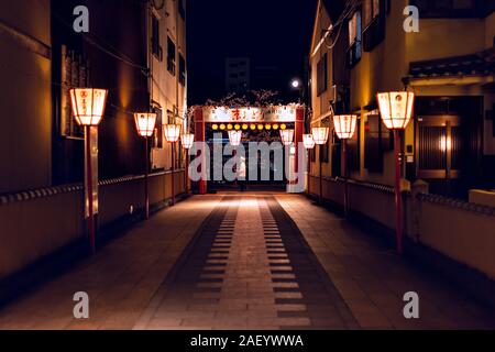 Kyoto, Japon - 9 Avril 2019 : ruelle étroite rue sombre dans la nuit dans le district de Gion la nuit avec le chef homme marchant et allumé en rangée de lanternes rouges Banque D'Images