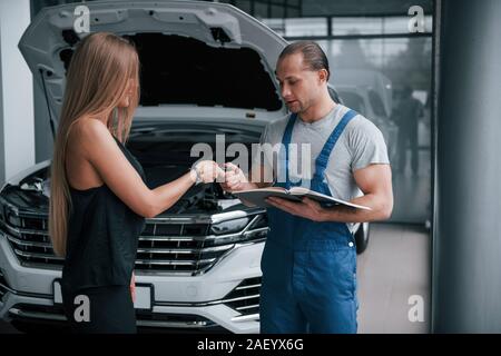Donner des clés. Résultats de la réparation. Homme confiant montrant quel genre de dommages sa voiture a été prise Banque D'Images