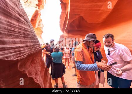 Page, USA - Le 10 août 2019 : groupe des gens parler de guider dans la fente d'Antelope Canyon en Arizona prendre photo avec téléphone Banque D'Images