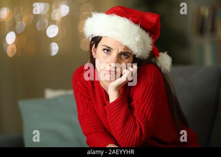 Femme frustrée sur vacances de Noël vous regarde assis sur un canapé à la maison dans la nuit Banque D'Images