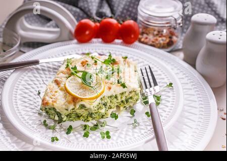 Lasagnes végétariennes aux épinards et microgreens sur une plaque blanche. Une alimentation saine et savoureuse. Banque D'Images