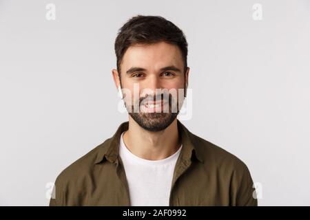 Homme barbu moderne vivant en milieu urbain, le port d'écouteurs sans fil de pointe d'écouter la musique et sourire insouciant, comme la qualité des écouteurs, vous promener city Banque D'Images