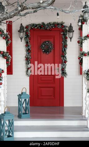 Une porte rouge décorée pour Noël avec des lanternes bleu sur l'escalier. Banque D'Images