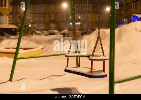 Teeter. Montagnes de neige dans la cour. Aire vide dans la nuit. Banque D'Images