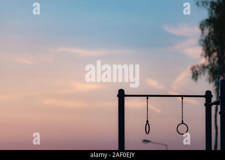 Anneaux de gymnastique sur la barre. Aire de jeux dans la cour au coucher du soleil. Banque D'Images