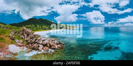 Vue panoramique aérienne impressionnante de Grand Anse Beach sur l'île de La Digue aux Seychelles. Les rochers de granit et l'océan turquoise lagoon avec des nuages blancs Banque D'Images