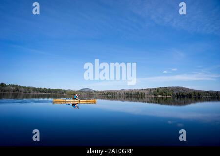 À bord de canots homme sous un ciel bleu sur un lac calme Banque D'Images