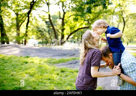 Père Fils holding sur les épaules en parc avec maman giving son baiser Banque D'Images