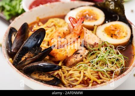 Vue en gros de fruits de mer épicés avec les moules et les crevettes de ramen dans un bol Banque D'Images