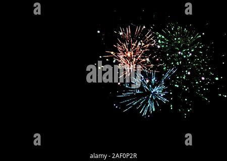 Bleu, vert et orange traditionnel feu d'artifice dans la nuit, isolée sur noir Banque D'Images