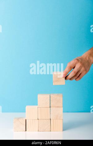 Portrait de l'homme mettre cube de bois sur blue with copy space Banque D'Images