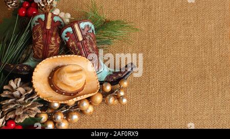 Bleu et marron et bottes de cowboy hat avec des pins, des pommes de pin et de baies sur un fond texturé tan with copy space Banque D'Images