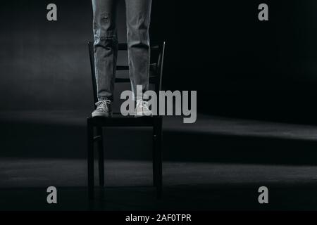 Portrait de l'auto-destructeur debout sur chaise et va se suicider sur fond noir Banque D'Images